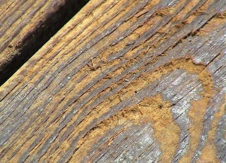 a section of wood from an outdoor deck that is damaged from incorrect power washing